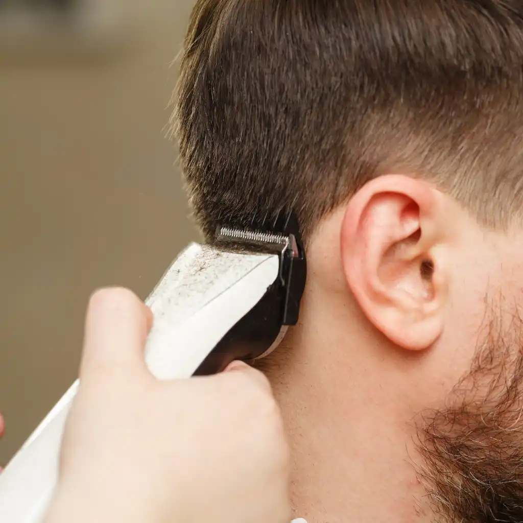 Hair cutting machine shaving the backside view of a young man